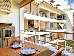 a balcony with a wooden table and a building at Manoa - Studio classé 2 étoiles à Saint-Denis in Saint-Denis