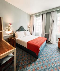 um quarto de hotel com uma cama com um cobertor vermelho em GRANDE HOTEL PARIS by STAY HOTELS em Porto