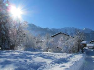 un patio cubierto de nieve con el sol en el cielo en Ferienwohnung Hartwimmer - Chiemgau Karte, en Inzell