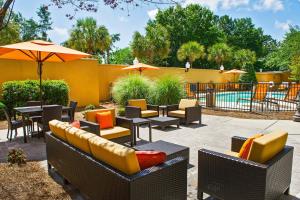 eine Terrasse mit Stühlen, Tischen und einem Sonnenschirm in der Unterkunft Courtyard by Marriott North Charleston Airport Coliseum in Charleston