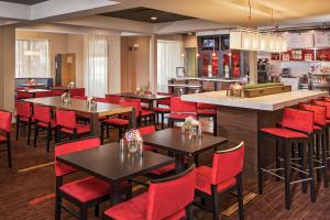 a restaurant with tables and red chairs and a bar at Courtyard by Marriott North Charleston Airport Coliseum in Charleston