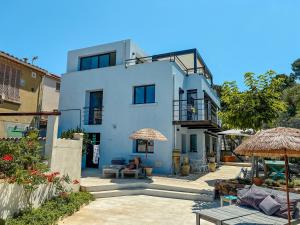 a white house with chairs and umbrellas in front of it at "Grand Bleu" Villa direkt am Meer in La Seyne-sur-Mer
