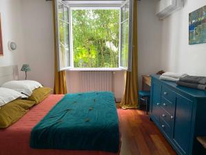 a bedroom with a bed with a blue dresser and a window at Appartement en rez de jardin in Ciboure