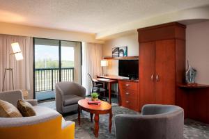 ein Hotelzimmer mit einem Wohnzimmer mit einem TV in der Unterkunft Courtyard by Marriott Jackson in Jackson