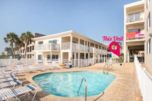 a swimming pool in front of a building with chairs at Emerald on the Water - Formerly Belleair Beach Club in Clearwater Beach