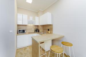 a kitchen with white cabinets and a table and stools at Apartament Słoneczny Ku Morzu by HolidaySun in Sianozety