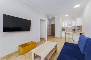 Apartament Słoneczny Ku Morzu by HolidaySun في سيانوزيتي: غرفة معيشة مع أريكة زرقاء وطاولة