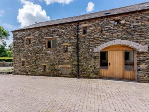 a stone barn with a wooden door and a brick driveway at The Mistal in Newby Bridge