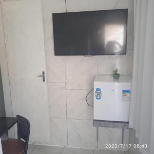 uma televisão pendurada numa parede com um frigorífico em POUSADA MEGA em Marataízes