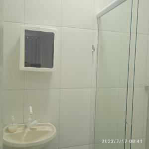 Baño blanco con lavabo y espejo en POUSADA MEGA, en Marataízes