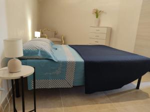 a bedroom with a bed with a blue blanket and a table at Brezza di mare in Punta Secca