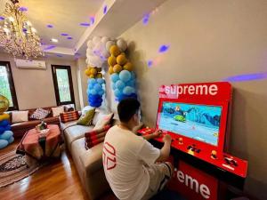 mężczyzna grający w grę wideo w salonie w obiekcie Unparalleled pool villa w mieście Bangkok