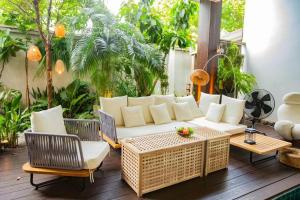 een terras met een witte bank, stoelen en bomen bij Unparalleled pool villa in Bangkok