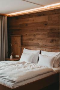 a bedroom with a large white bed with a wooden wall at Hotel Rosenhof Murau in Murau