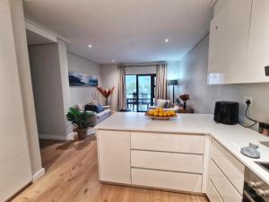a kitchen with white cabinets and a living room at 116 The Esplanade in Hermanus