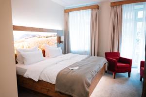 a bedroom with a large bed and a red chair at Hotel Rodderhof in Bad Neuenahr-Ahrweiler