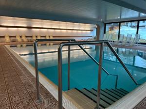 a swimming pool with stairs and chairs in a building at Appartementhaus Birkenwald in Seefeld in Tirol