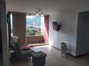 a living room with a chair and a large window at Mayorca cómodo y central in Sabaneta