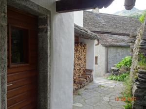 una casa con un montón de madera al lado de una puerta en Casa Sonnenberg en Bosco Gurin