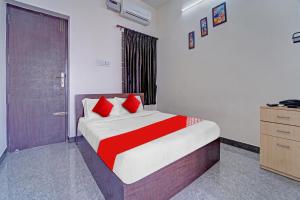 1 dormitorio con 1 cama con almohadas rojas en Super OYO Flagship Royal Residency, en Nāmakkal