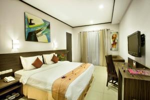 een slaapkamer met een bed, een bureau en een televisie bij Summer Hills Hotel & Villas Bandung in Bandung