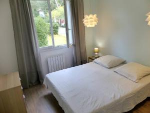 ein Schlafzimmer mit einem weißen Bett und einem Fenster in der Unterkunft Villa ONGUI ETHORRI Villa pour 6 ou 8 personnes Wifi gratuit in Soorts-Hossegor