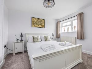 a white bedroom with a large white bed and a window at Pass the Keys Stylish Flat Close To Beach in Chichester