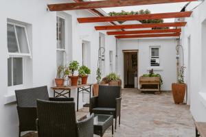 a patio with chairs and a table with potted plants at Bonne Esperance, Simon's Town in Simonʼs Town