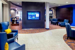 a waiting room with blue chairs and a tv on a wall at Courtyard by Marriott Montgomery Prattville in Prattville