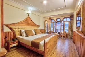 a bedroom with a large bed with a wooden headboard at Goroomgo i Bex Manali Near Mall Road- Best Choice of Travellers in Manāli