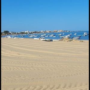een zandstrand met boten in het water bij Apartamento las tres lunas in Sanlúcar de Barrameda
