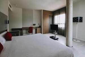 a bedroom with a large white bed and a television at Hotel K10 in Urnieta