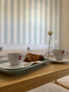 una mesa con dos tazas de café y un plato de cruasanes en Il Faro beach house, en Marina di Pisa