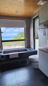 a bathroom with a tub and a toilet and a window at La View Homestay in Manzhou