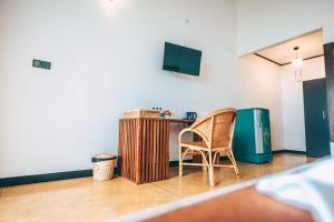 einen Stuhl in einem Zimmer mit einem Schreibtisch und einem TV in der Unterkunft Samudra Beach Resort in Tangalle