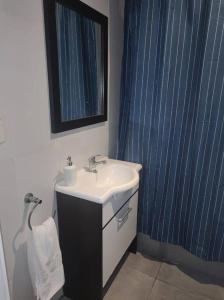 a bathroom with a sink and a blue shower curtain at Impecable departamento en Caballito. in Buenos Aires