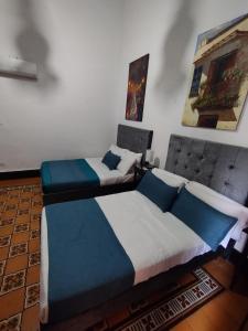 2 Betten in einem Zimmer mit Gemälden an der Wand in der Unterkunft Boutique Portón De Granada in Cali