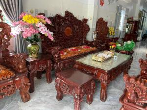 a living room with a couch and tables and flowers at Nhà Nghỉ Liên Hòa in Ha Tien