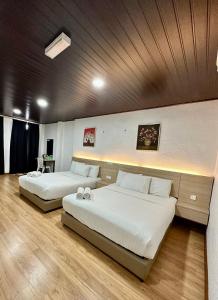 two beds in a large room with wooden floors at Kangar Hotel Sdn Bhd in Kangar