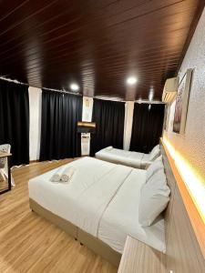 two beds in a room with black curtains at Kangar Hotel Sdn Bhd in Kangar