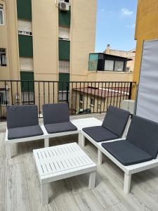 3 sillas y una mesa en el balcón en MALAGA INN APARTAMENTS, en Málaga