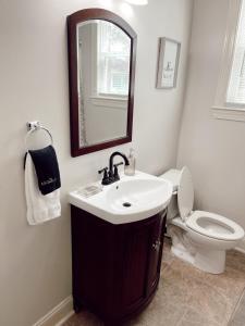 a bathroom with a sink and a toilet and a mirror at Luxury Home near South Historic District in Coffeyville
