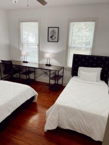 a bedroom with two beds and a desk and two windows at Luxury Home near South Historic District in Coffeyville