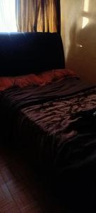 a bed sitting in a room with a window at Akira Safaris Furnished Apartment in Migori