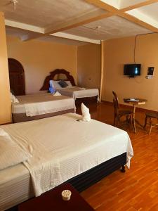 um quarto de hotel com duas camas e uma televisão em Hotel y Restaurante La Perla, Cacaopera, Morazan, El Salvador em Cacaopera