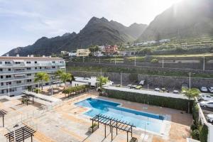 バハマルにあるATICO VISTAS AL MAR Y AL TEIDE EN RESIDENCIAL ARMONIA PARK (BAJAMAR) TENERIFEのプールと山々を背景にしたホテル