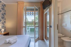 a hotel room with a bed and a bathroom with a balcony at Hotel Riva Etrusca in Marina di Bibbona