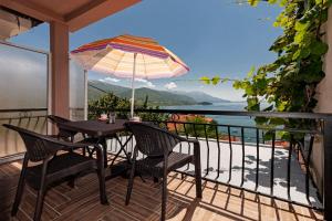 een tafel en stoelen op een balkon met een parasol bij The Lakeside Haven in Ohrid
