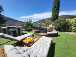 a garden with a white couch and a fire place at Villa Palmire, large terrace with jacuzzi available in La Turbie