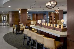 a hotel lobby with a bar and chairs at Courtyard by Marriott Saratoga Springs in Saratoga Springs
